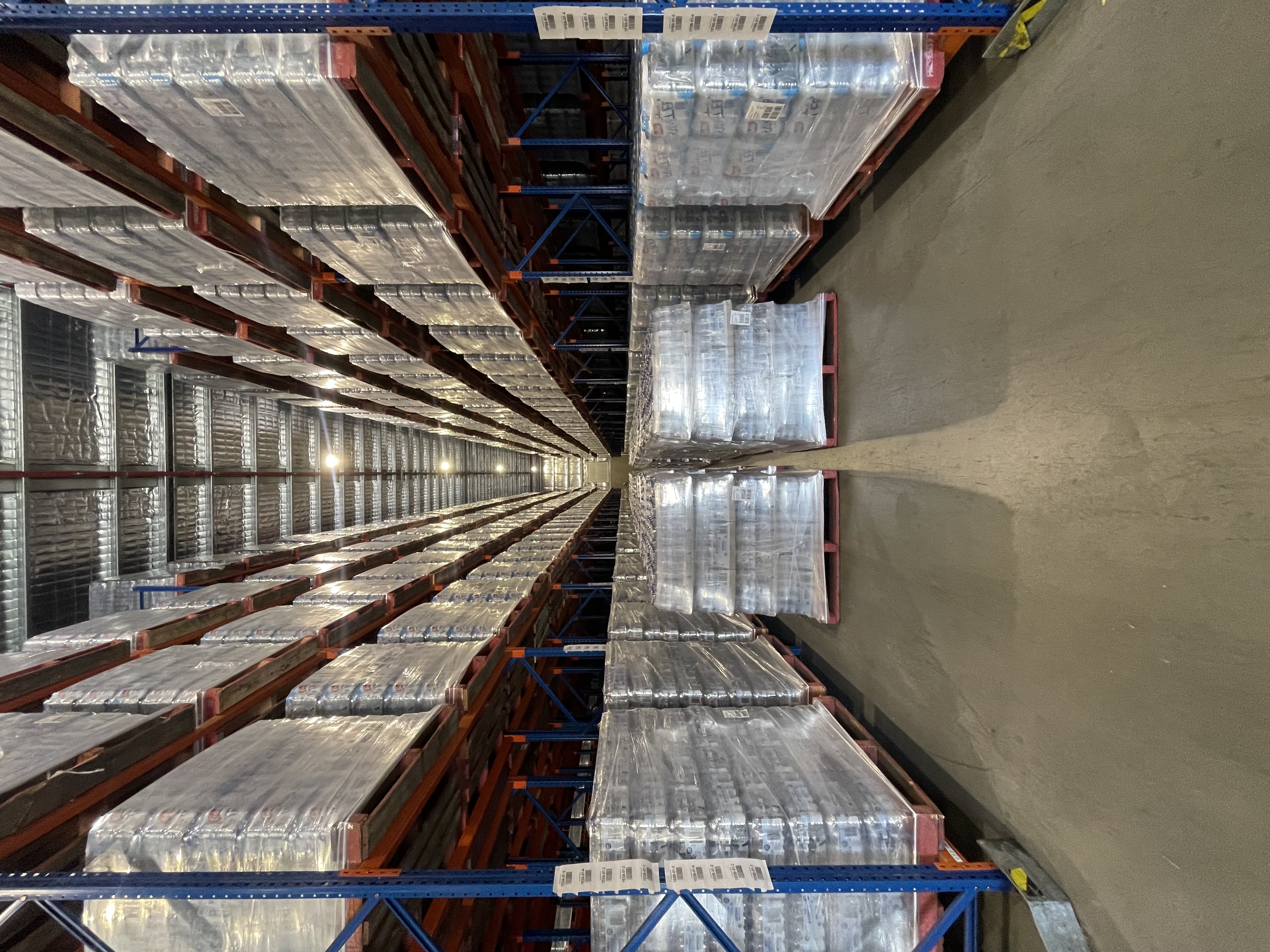 An aisle of warehouse racking filled with wrapped pallets