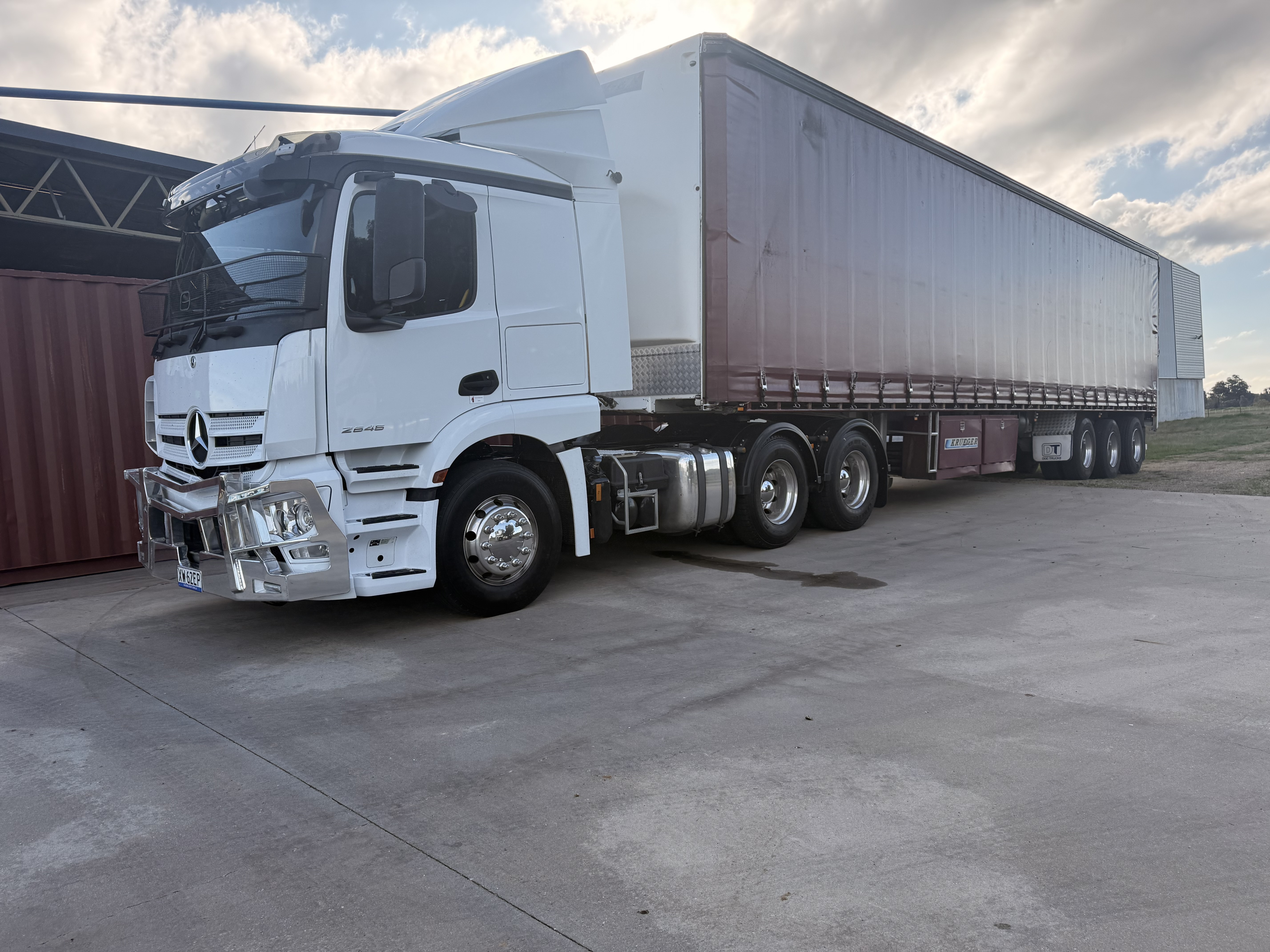 A white prime mover with a curtain-sided trailer