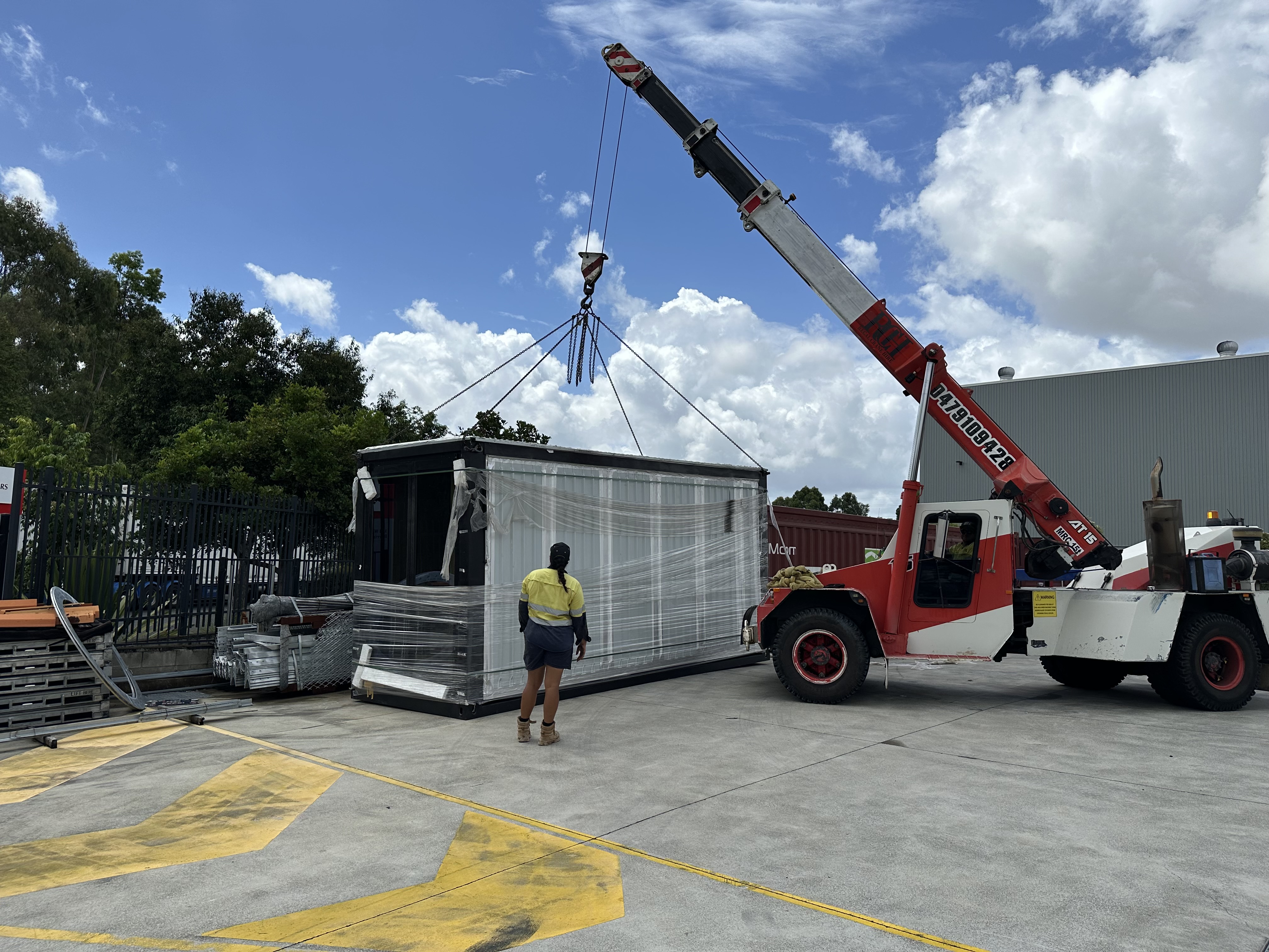 A mobile crane handling a wrapped structure in a freight yard