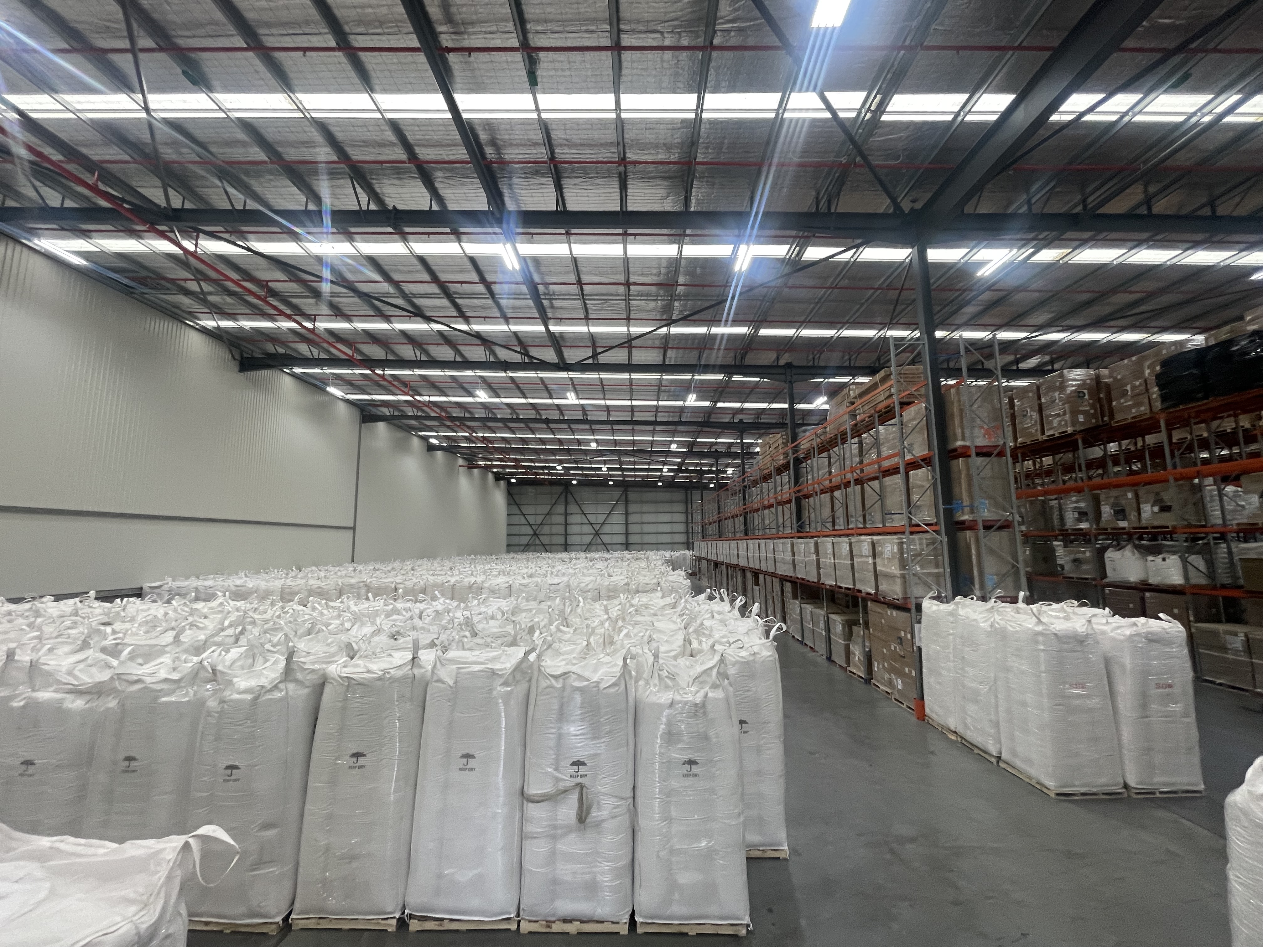 Bulk bags arranged beside stocked warehouse racks