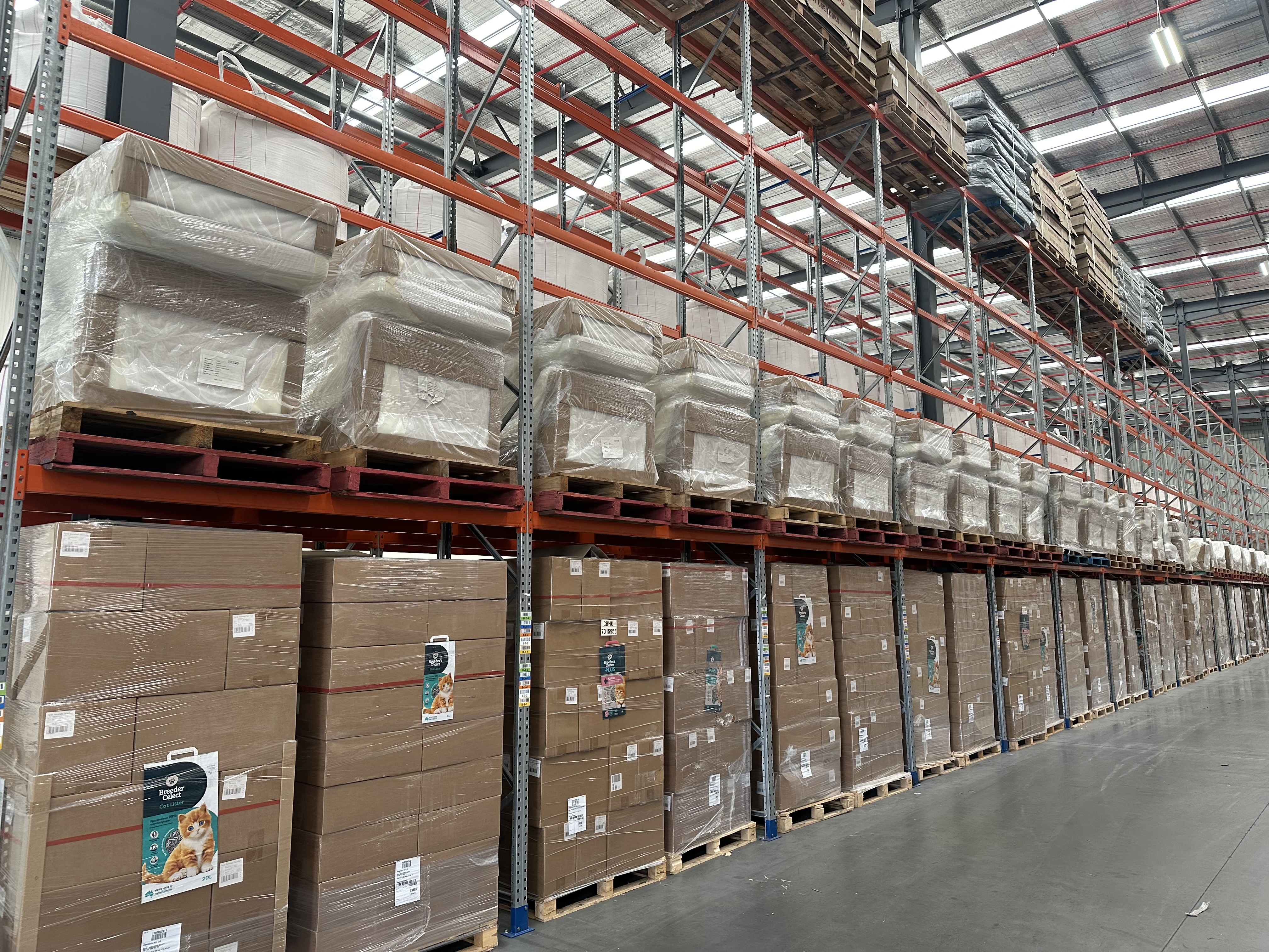 Wrapped pallets of boxed goods on warehouse shelving