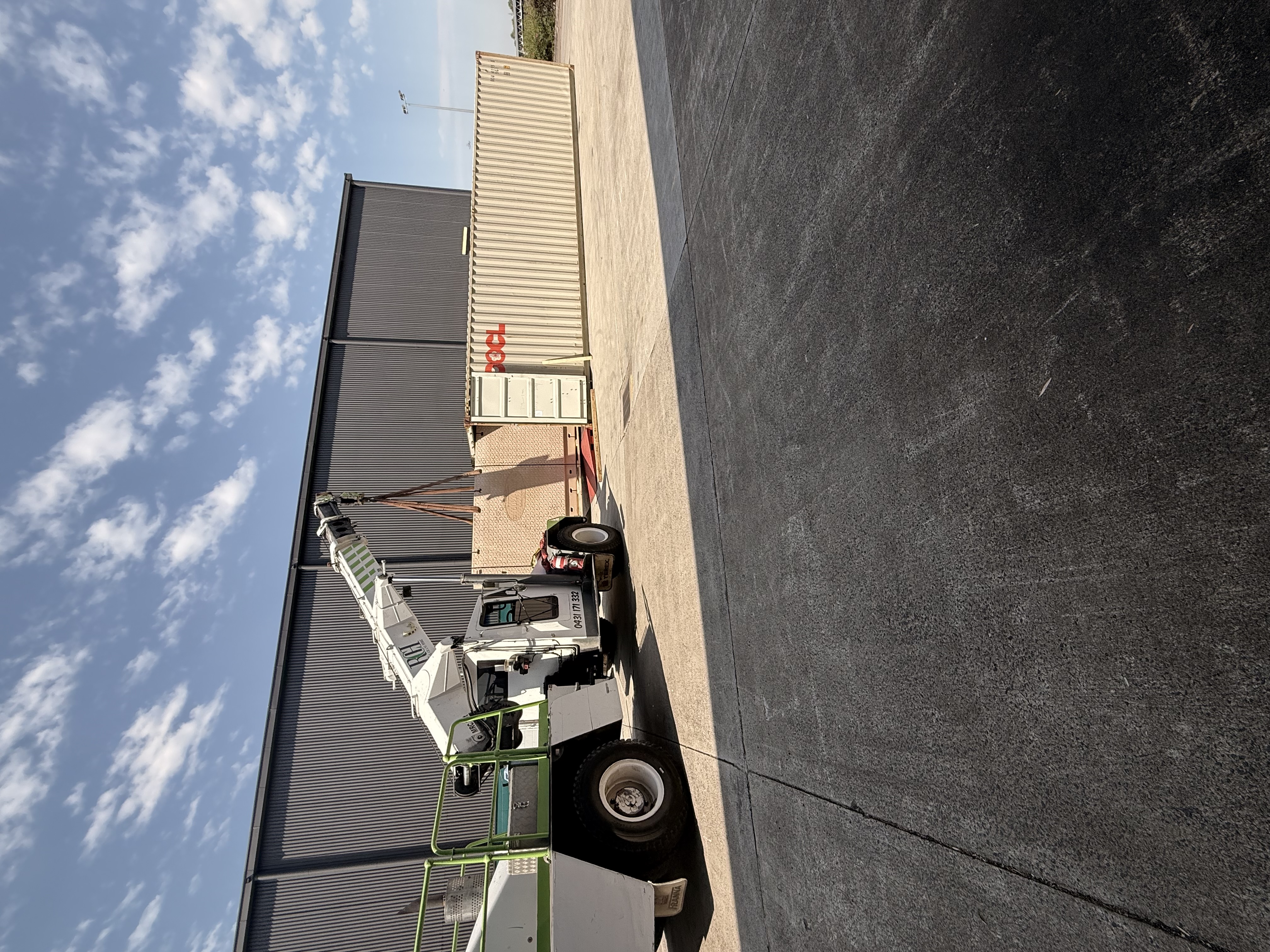 A crane lifting crated freight beside an open shipping container